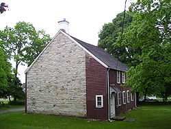 A brick house with a white chimney and red roof.