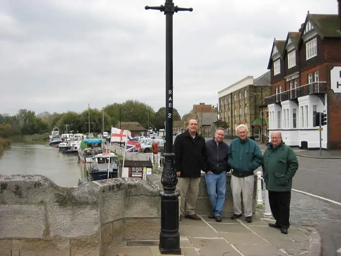 Four men standing next to a street light.